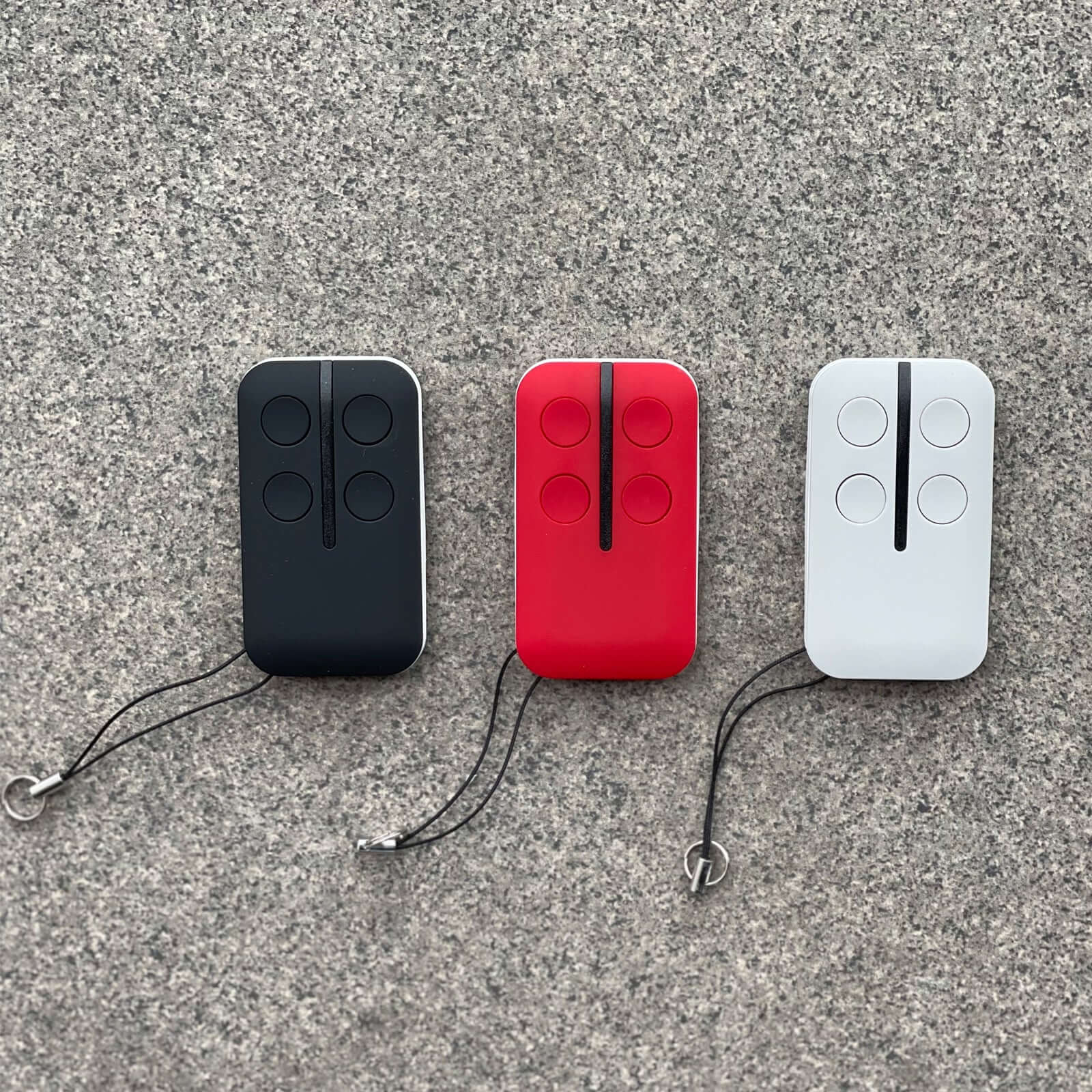 Black, red, and white ATA PTX5 PTX-5 TrioCode garage door remotes compatible with GDO models displayed on a stone surface.