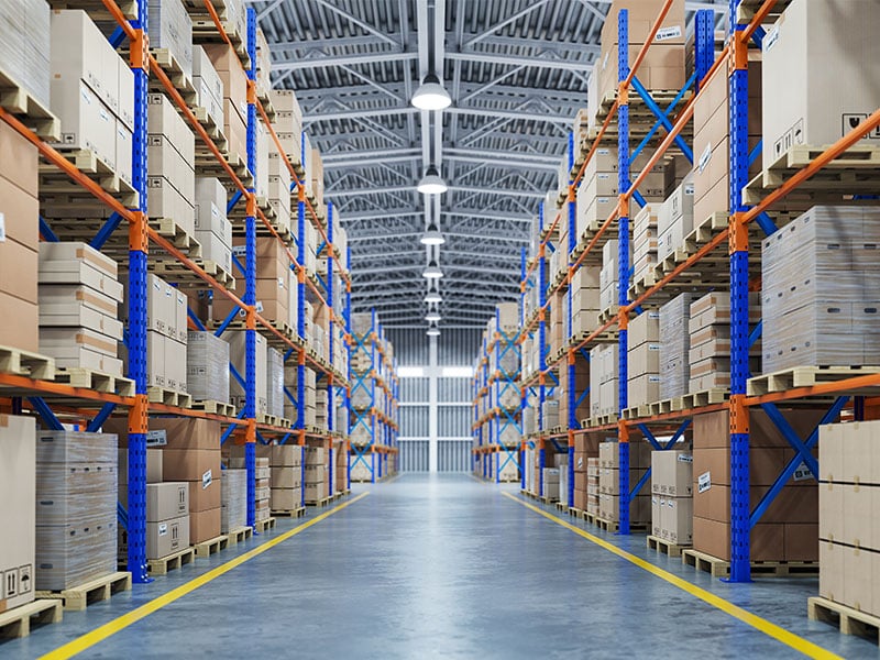 Spacious modern warehouse with high shelves filled with stacked boxes and efficient lighting system.