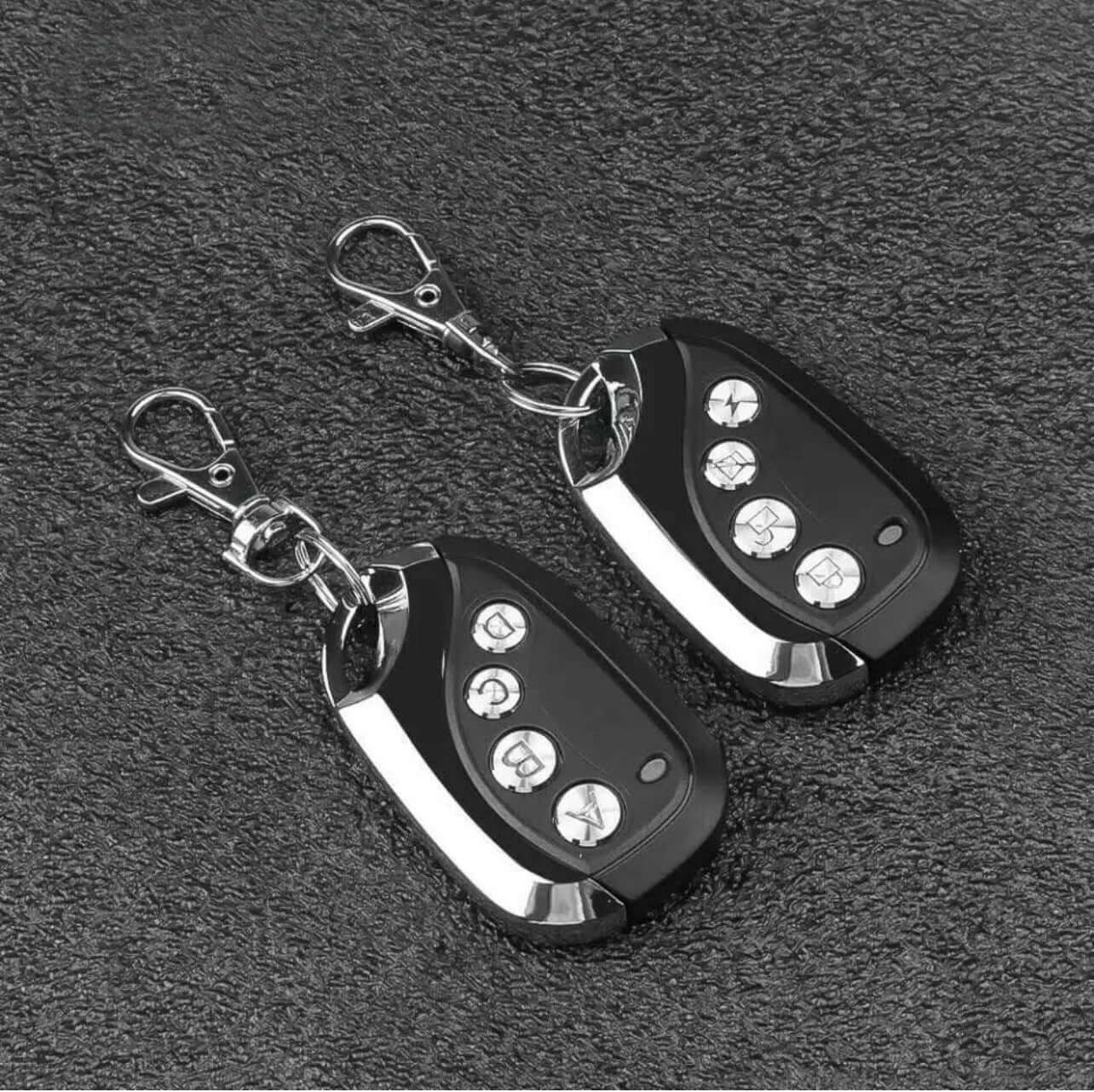 Two BND B&D MPC3 TX315 compatible garage gate remote duplicators on a textured surface with keyrings.