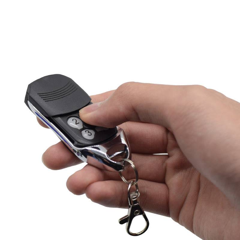 Person holding Ditec compatible remote control with keyring for garage and gate access.