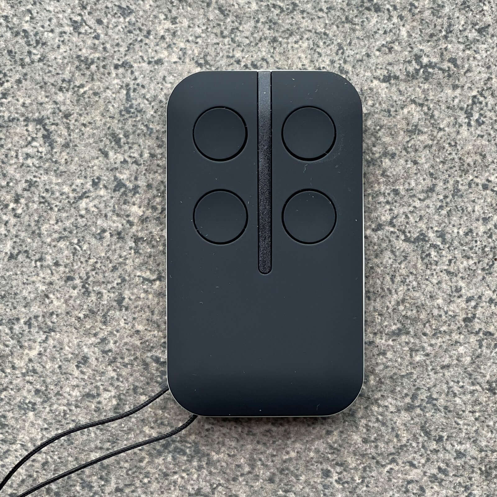 FAAC compatible remote control for garage doors, featuring four buttons, Garageway brand accessory on a stone background.