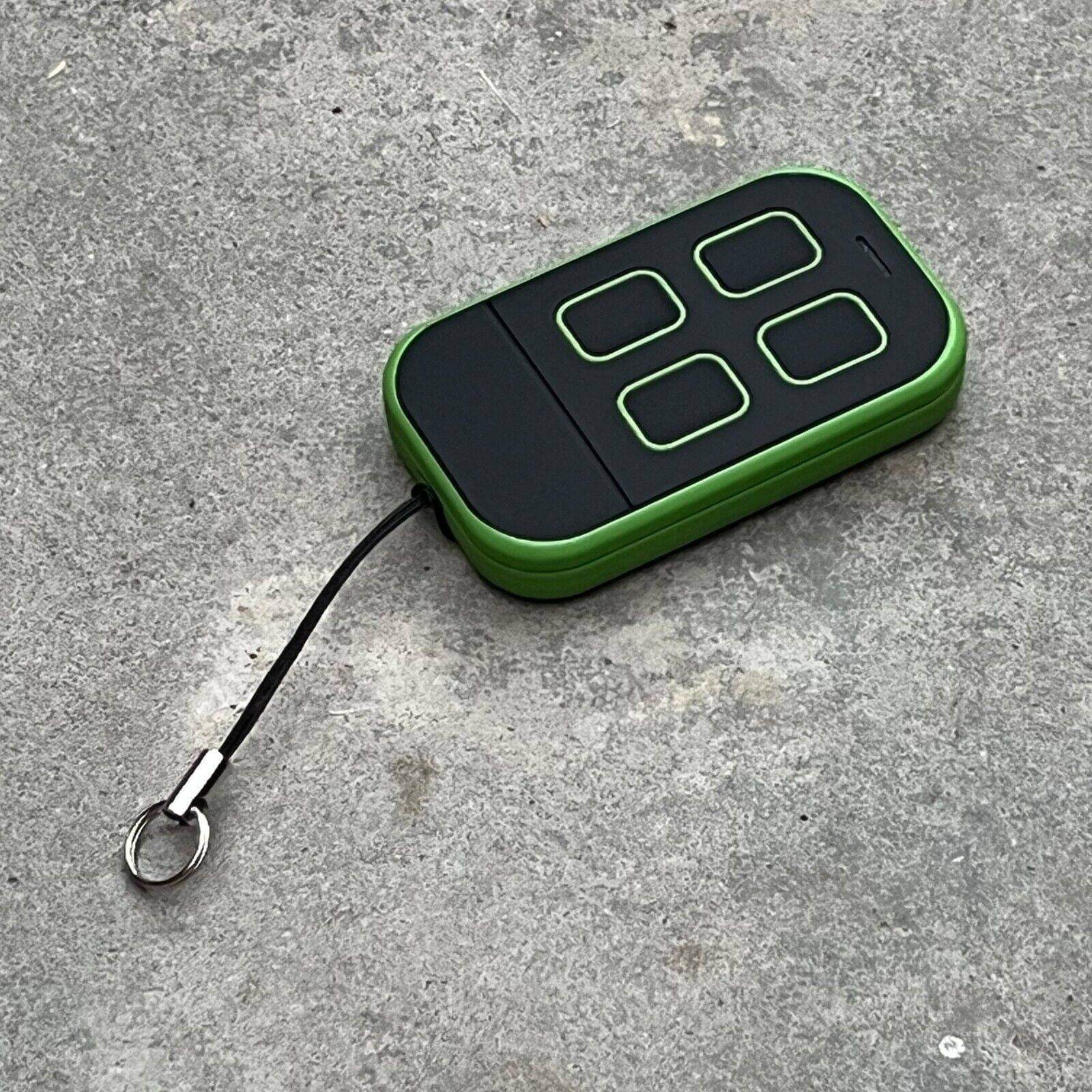 Merlin+ C945 compatible remote control with green casing and four buttons on a gray surface.